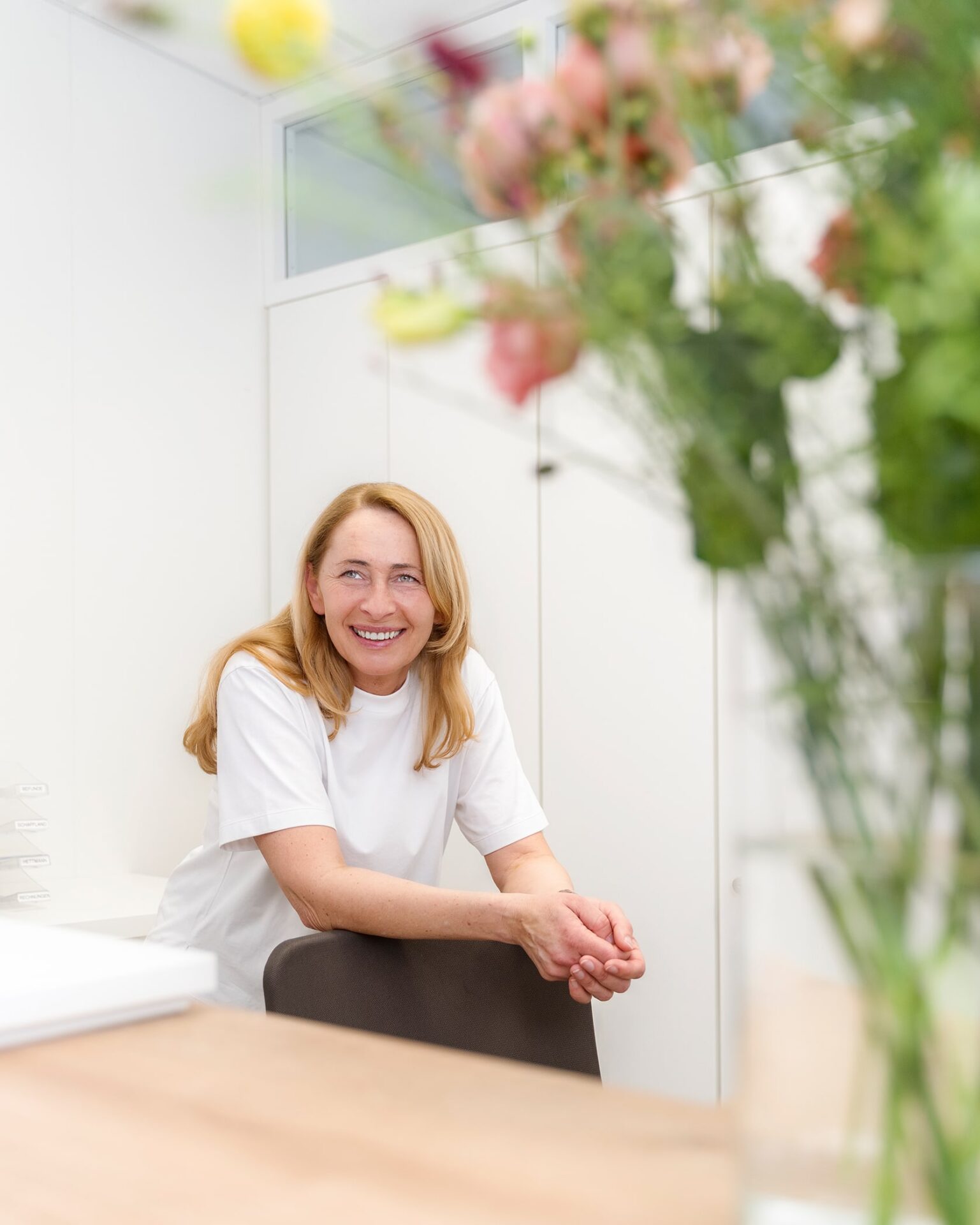 Mitarbeiterin sitzt an Rezeption der gynäkologischen Praxis Stuttgart-Heslach. Rechts auf der Theke ist ein Blumenstrauß.